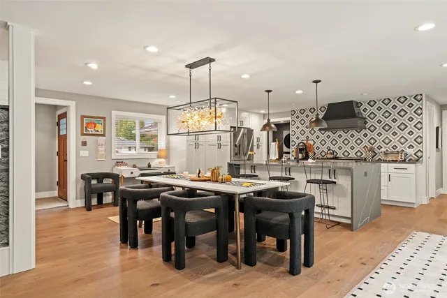 a kitchen with stainless steel appliances kitchen island granite countertop a table chairs sink and cabinets