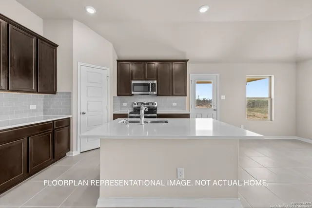 a large kitchen with kitchen island granite countertop a sink and a stove top oven with wooden floor