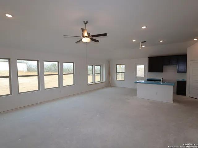 a view of an empty room with a kitchen and a window