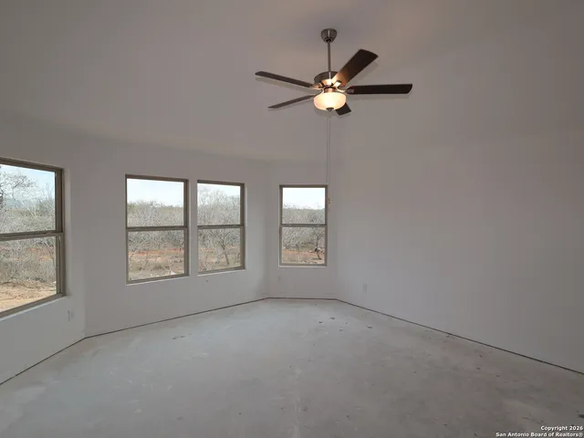 an empty room with chandelier fan and windows