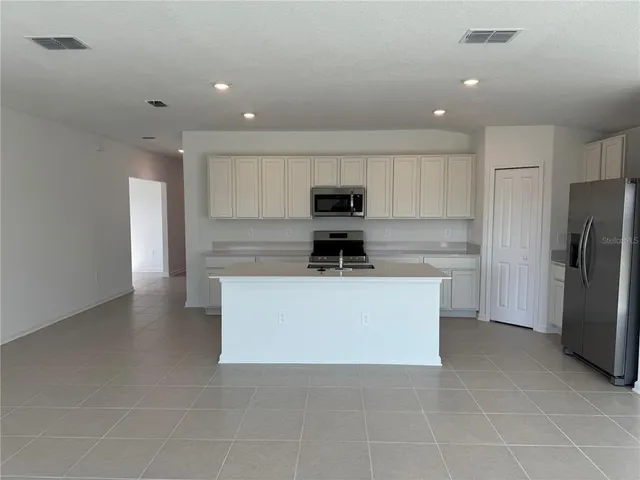 a kitchen with a refrigerator a stove top oven and white cabinets