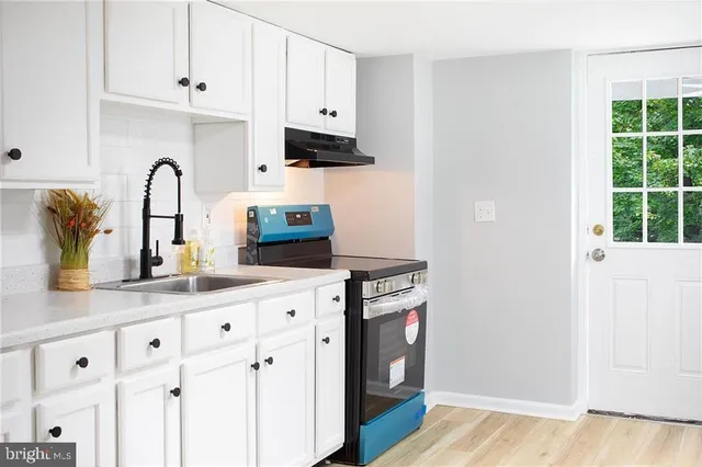 a kitchen with granite countertop white cabinets and a wooden floor