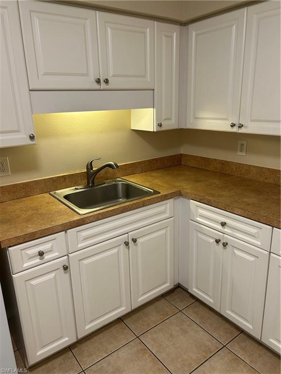 Kitchen with white cabinets, light tile patterned floors, and dark countertops