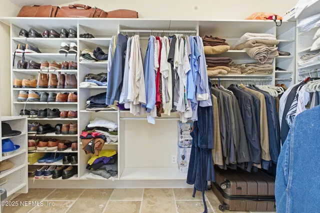 a view of walk in closet with clothes and shoes