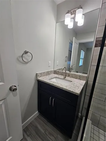 a bathroom with a granite countertop sink a light fixture and a mirror