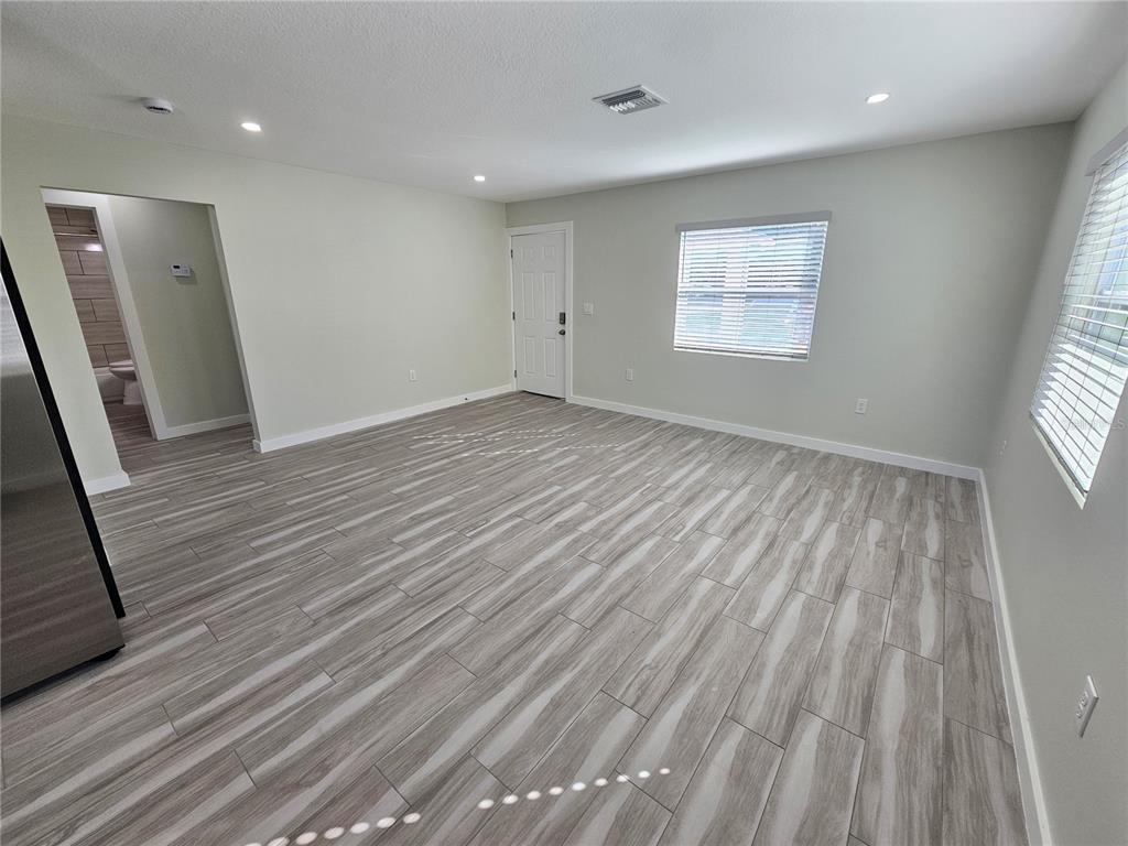 7043 Brentford Road Sarasota, FL 34241 - Photo 4 of 19 an empty room with wooden floor and windows