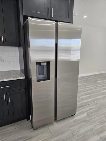 a close view of a refrigerator in kitchen and an empty room