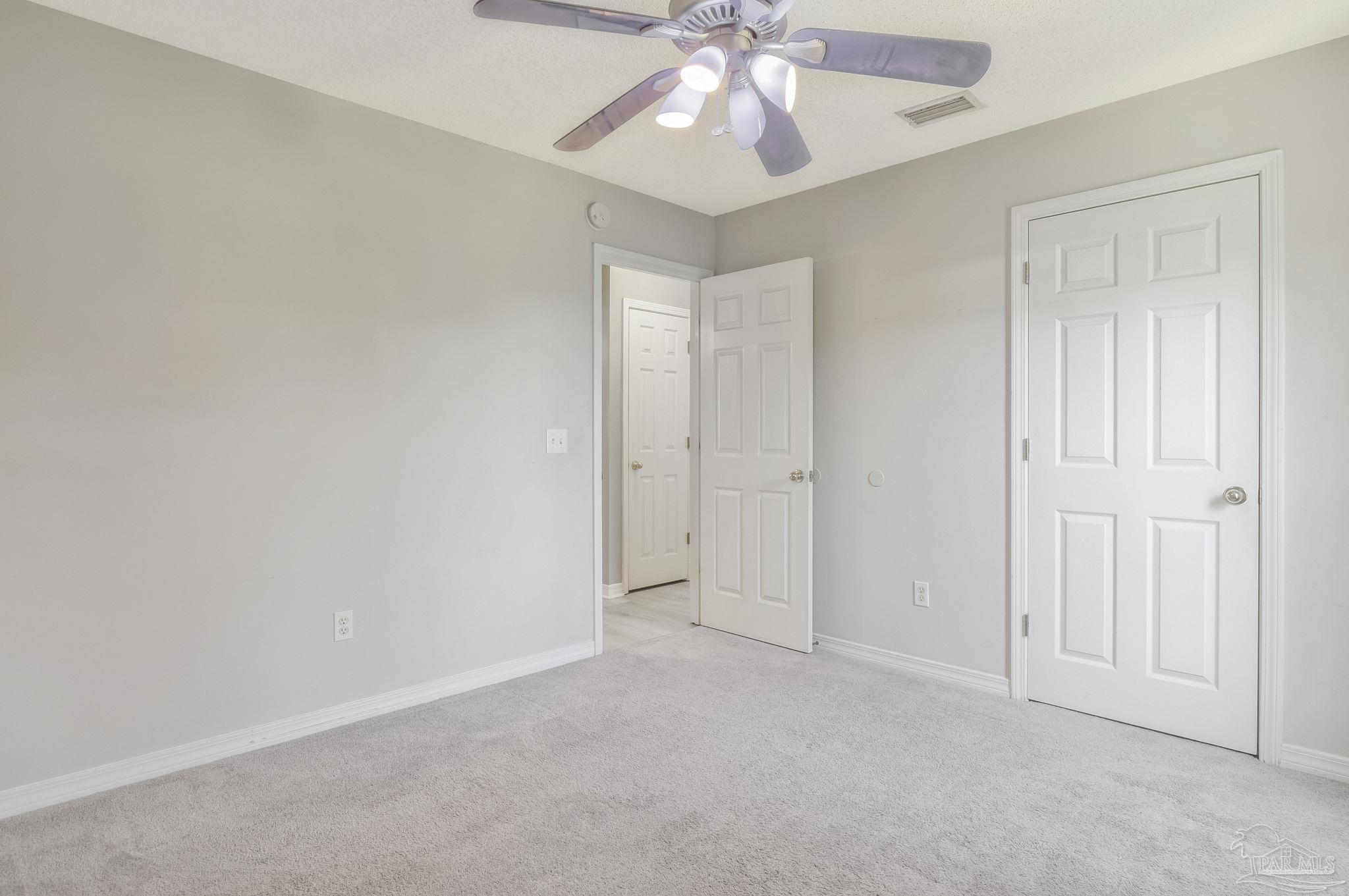 5539 Windrun Place Pace, FL 32571 - Photo 18 of 62 an empty room with a chandelier fan and windows