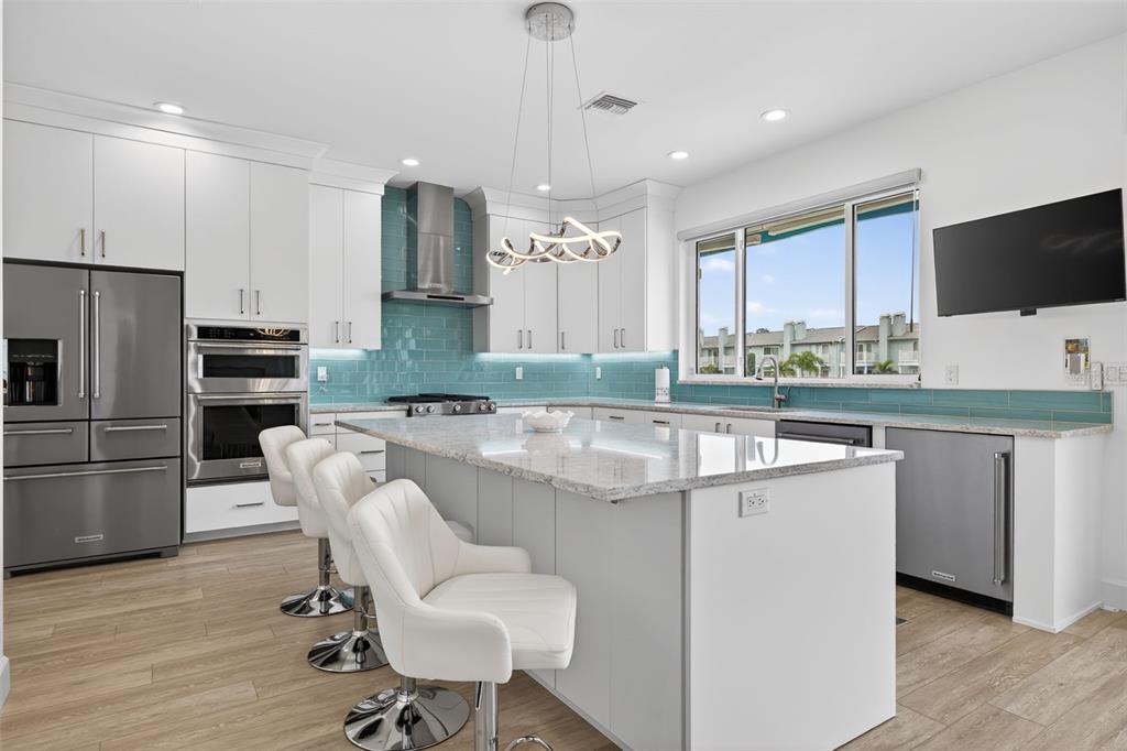 314 6th Avenue Indian Rocks Beach, FL 33785 - Photo 13 of 60 a kitchen with stainless steel appliances granite countertop a stove top oven a refrigerator a sink and chairs