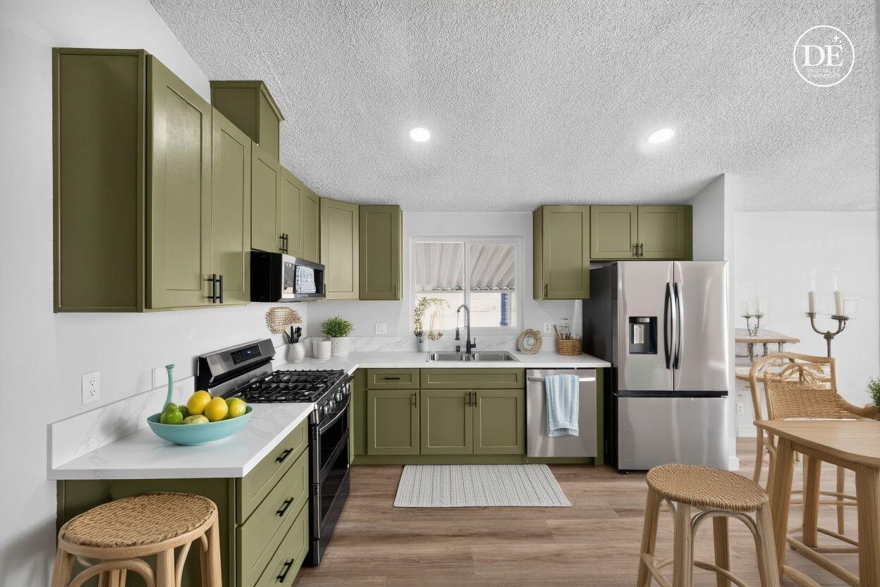 15181 Van Buren Boulevard, Unit 102 Riverside, CA 92504 - Photo 12 of 29 a kitchen with stainless steel appliances a stove a sink a refrigerator and chairs