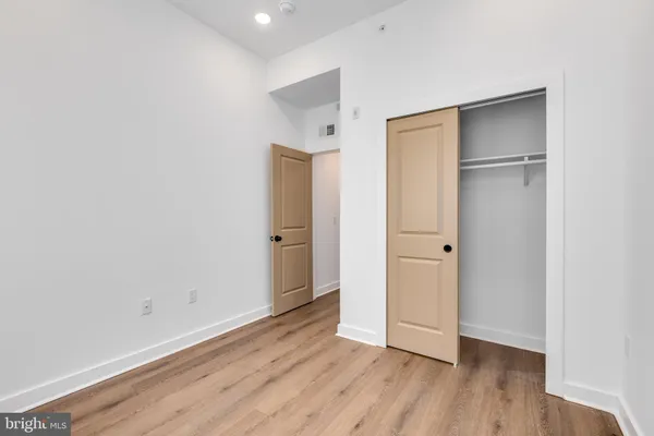 a view of an empty room with wooden floor and closet