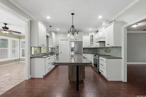a kitchen with stainless steel appliances granite countertop a refrigerator a stove and a wooden floors