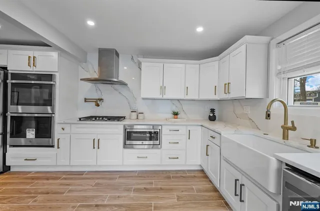 a kitchen with stainless steel appliances granite countertop a stove and white cabinets
