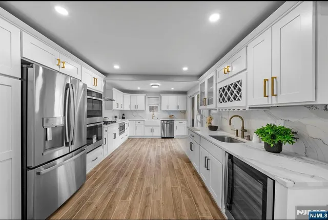 a kitchen with stainless steel appliances a refrigerator sink and white cabinets