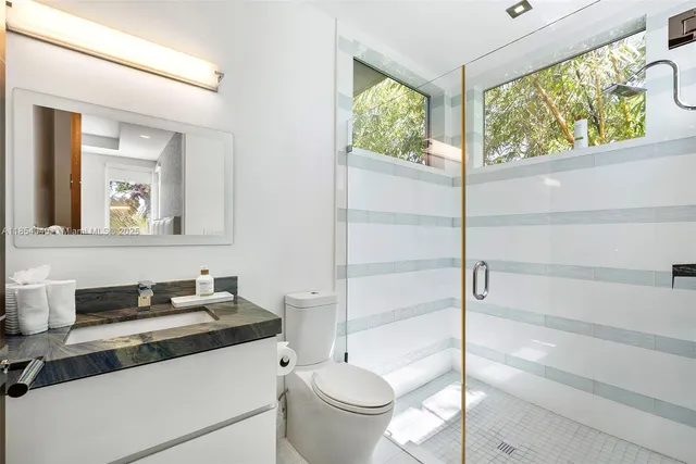 a spacious bathroom with a granite countertop sink a mirror and a bathtub