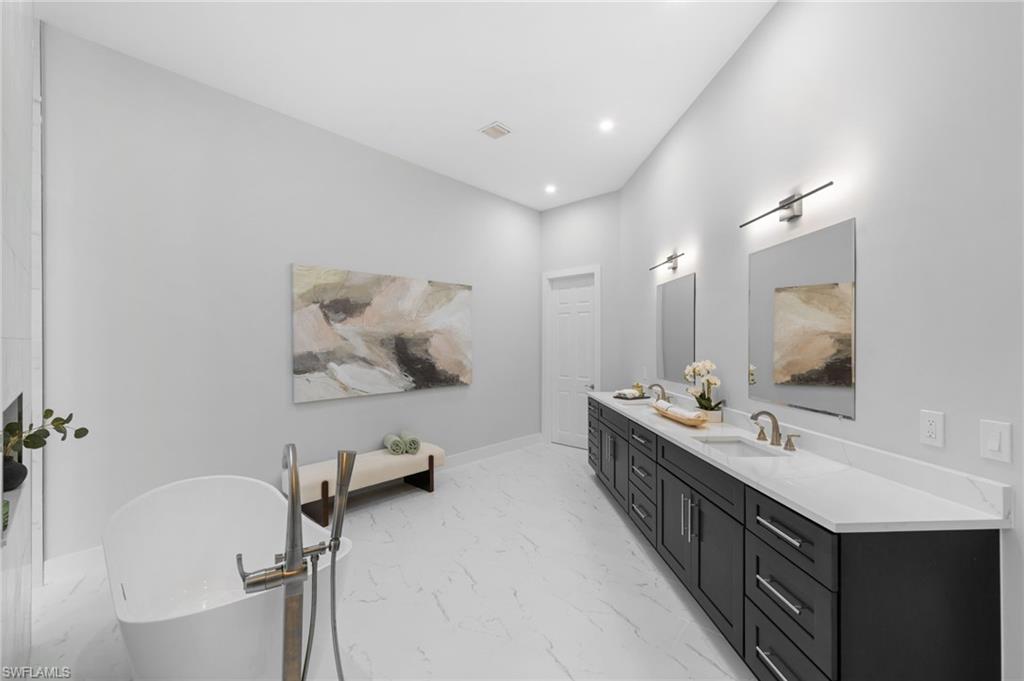 7834 Classics Drive Naples, FL 34113 - Photo 28 of 50 a bathroom with a double vanity sink a mirror and a bathtub