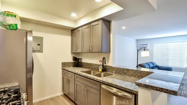 a kitchen with granite countertop a sink stainless steel appliances and cabinets