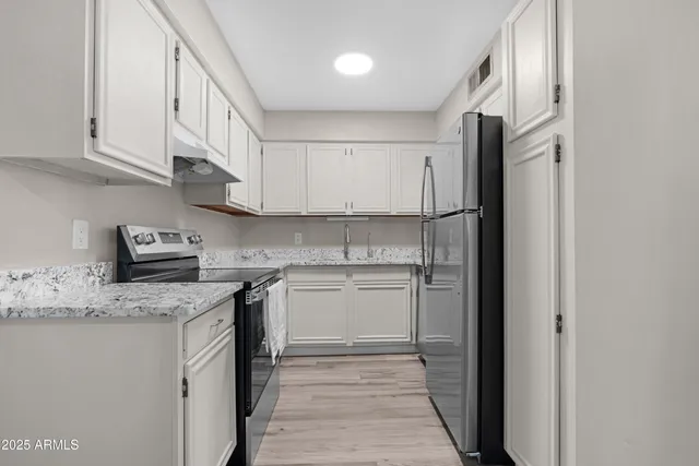 a kitchen with stainless steel appliances granite countertop a sink and a refrigerator