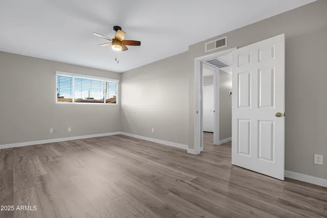 a view of an empty room with wooden floor and window