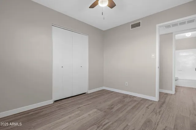 a view of an empty room with wooden floor and a ceiling fan