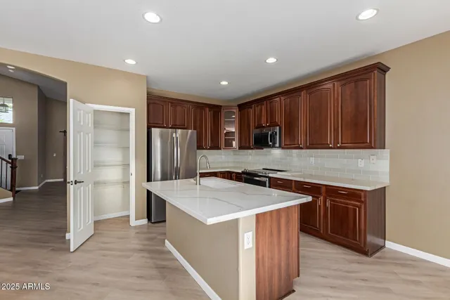 a kitchen with stainless steel appliances granite countertop a sink a stove and refrigerator