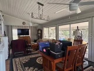 a living room with furniture a ceiling fan a flat screen tv and a large window