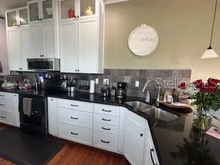 a kitchen with granite countertop a white cabinets and wooden floor