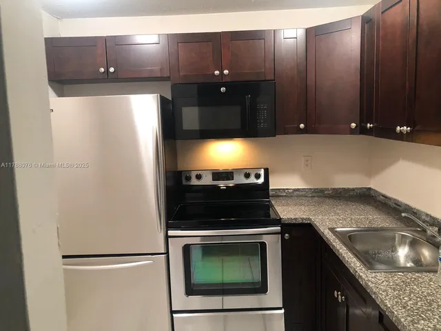a kitchen with granite countertop a refrigerator and a sink
