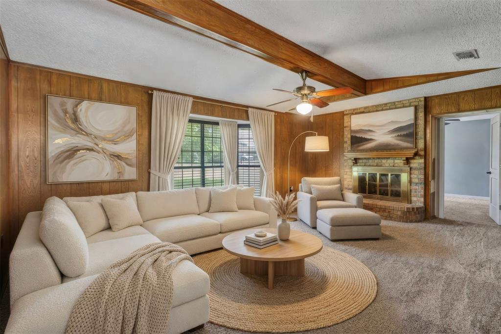 108 Prairie Creek Road Red Oak, TX 75154 - Photo 2 of 19 VIRTUALLY STAGED Spacious living area featuring wood-paneled walls, exposed wood beams, and a brick fireplace