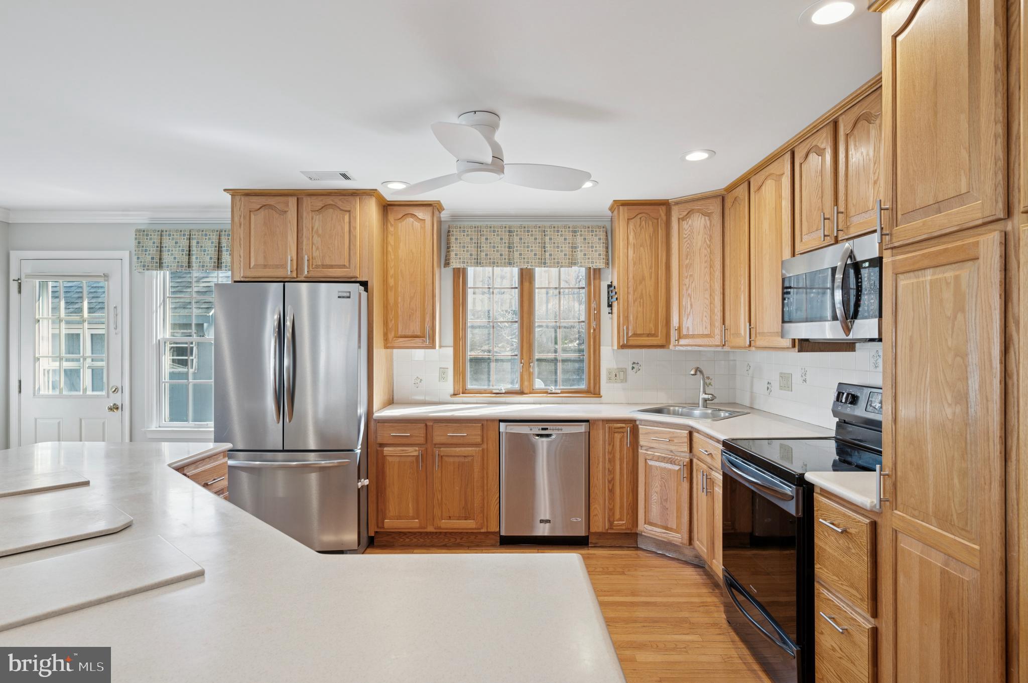 946 Georgetown Road Swarthmore, PA 19081 - Photo 10 of 36 a kitchen with stainless steel appliances granite countertop a refrigerator a sink dishwasher a stove and white countertops with wooden floor