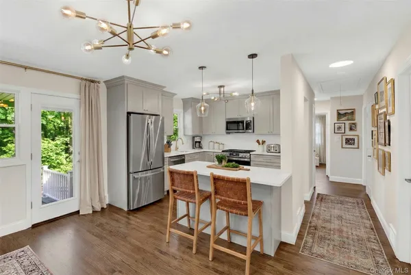 a kitchen with stainless steel appliances kitchen island granite countertop a refrigerator a stove a microwave oven a dining table and chairs with wooden floor