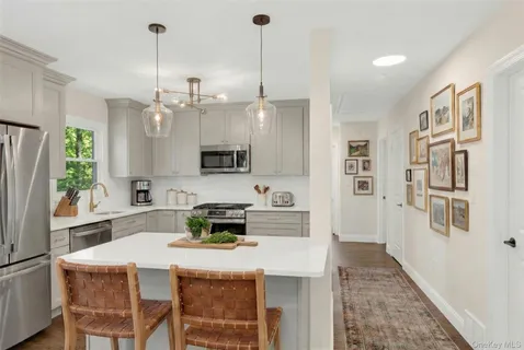 a kitchen with stainless steel appliances kitchen island granite countertop a sink refrigerator and cabinets