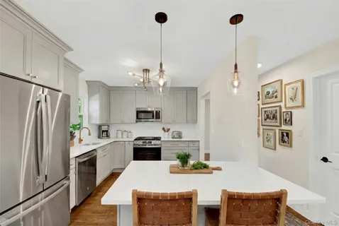 a kitchen with stainless steel appliances kitchen island granite countertop a refrigerator a stove and a sink with dishwasher