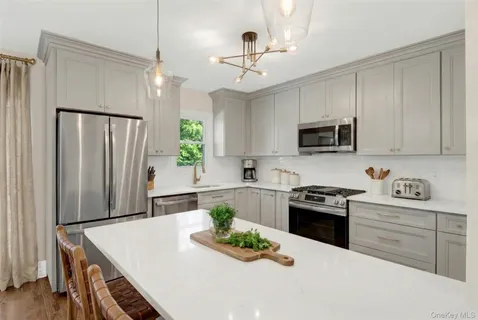 a kitchen with stainless steel appliances granite countertop a refrigerator a stove a sink dishwasher and white cabinets with wooden floor