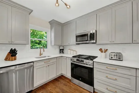 a kitchen with white cabinets appliances a sink and a window
