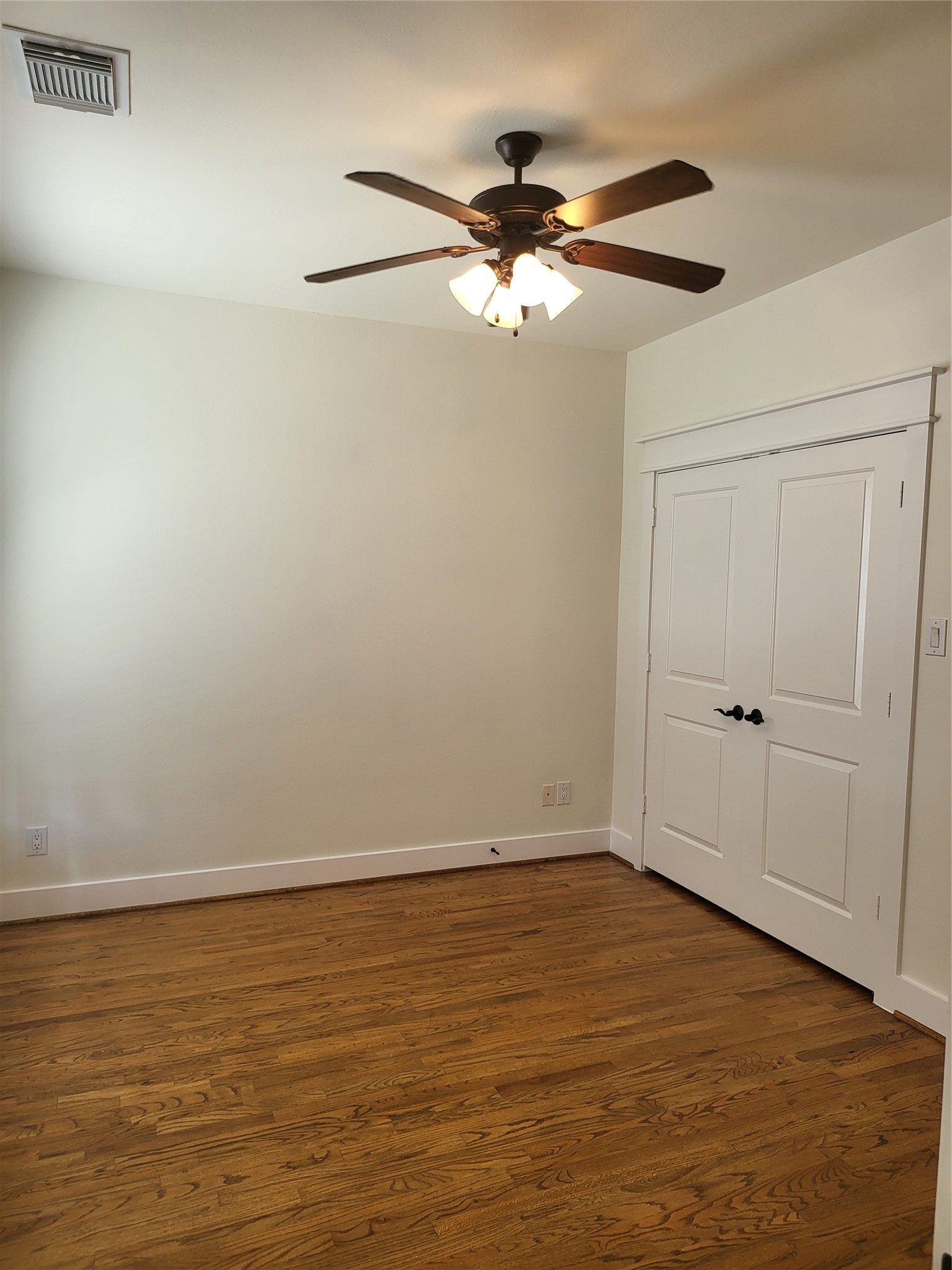 2423 Roufa Road Houston, TX 77003 - Photo 14 of 22 The upstairs bedroom has a double-door closet that includes shelving, a ceiling fan, and hardwood floors.