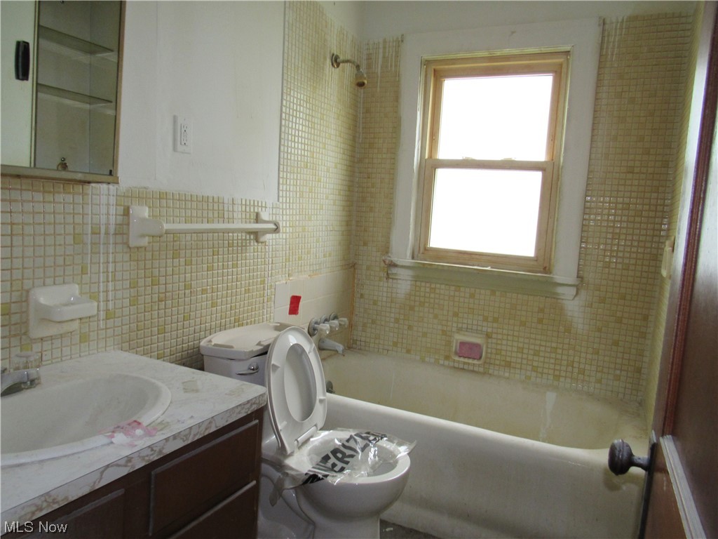 17815 Olympia Road Cleveland, OH 44112 - Photo 16 of 27 Full bathroom with toilet, backsplash, tile walls, vanity with extensive cabinet space, and tiled shower / bath combo