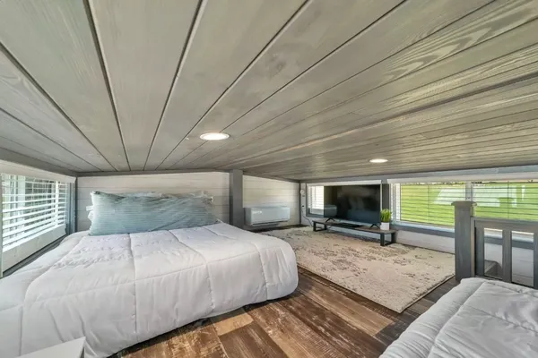 a spacious bedroom with a large bed a flat tv screen and dresser