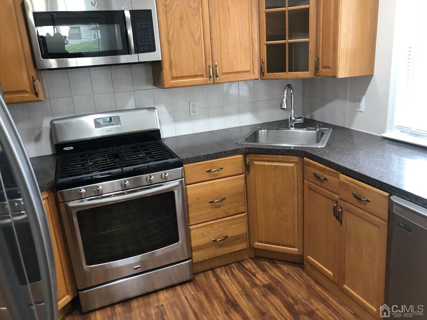420 Cross Road, Unit B11 Matawan, NJ 07747 - Photo 2 of 9 a kitchen with granite countertop cabinets stainless steel appliances and wooden floor