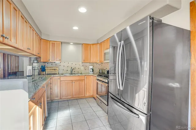 a kitchen with stainless steel appliances granite countertop a refrigerator and a sink