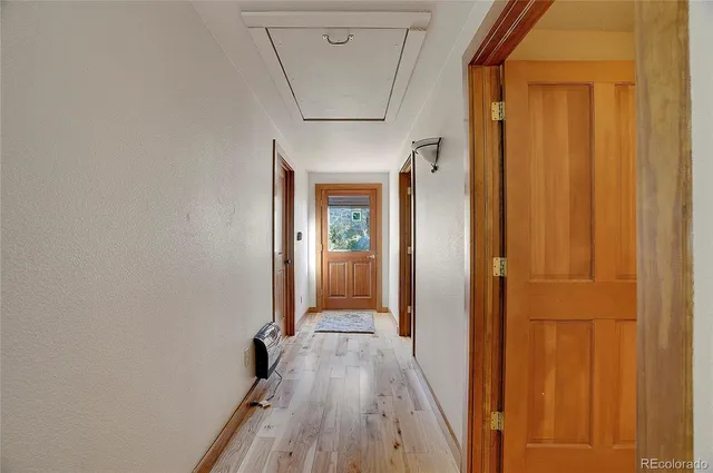 a view of a hallway with wooden floor and a bathroom