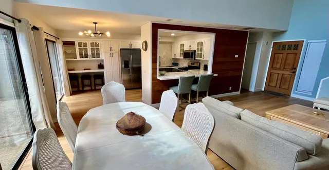 a living room with stainless steel appliances furniture a rug and a kitchen view