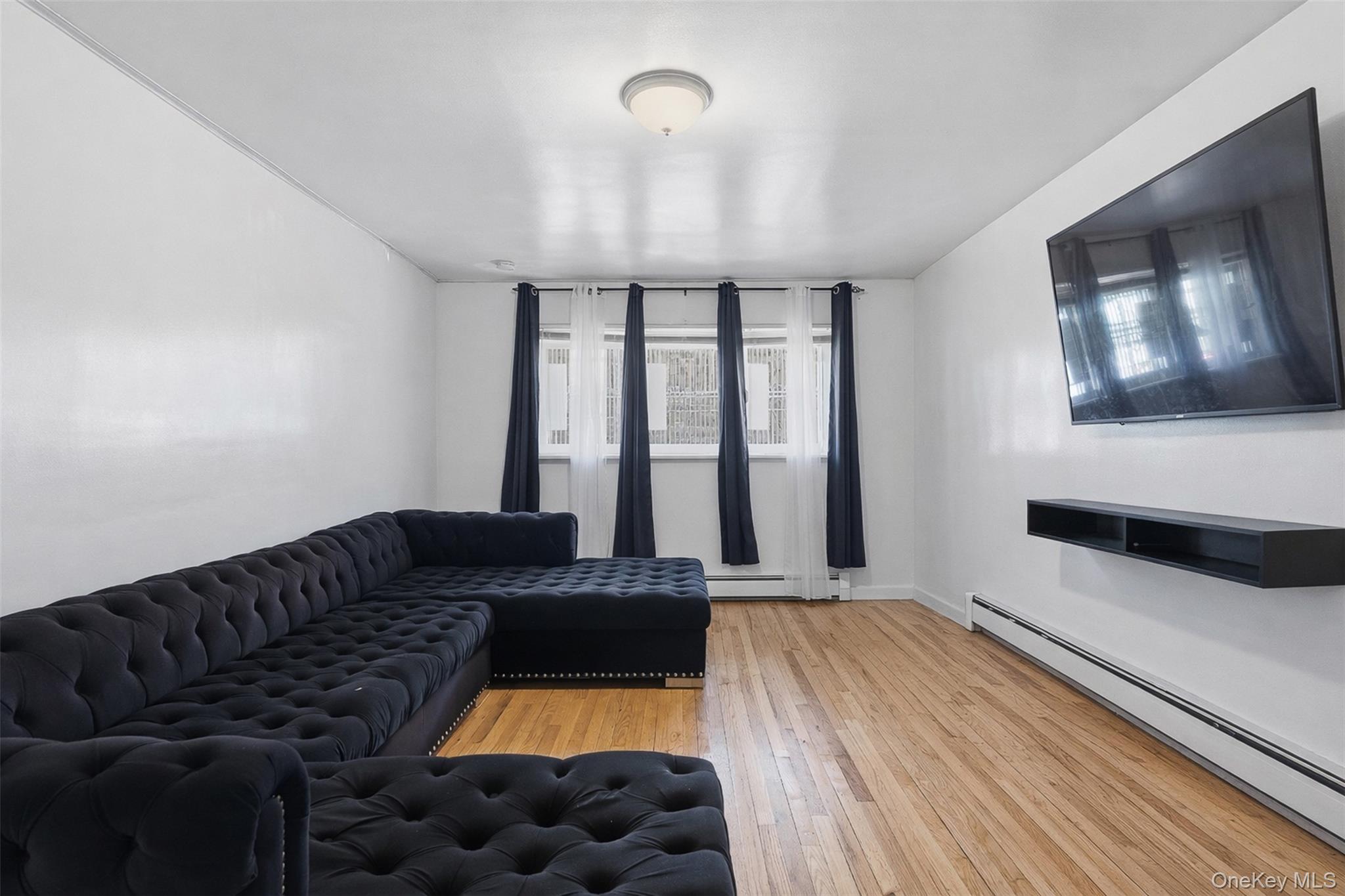 1677 Unionport Road Bronx, NY 10460 - Photo 6 of 33 Living area with a baseboard radiator and light wood finished floors