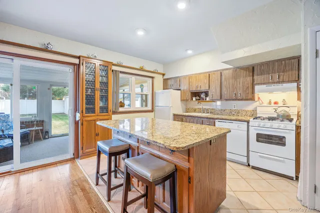 a kitchen with granite countertop wooden floors and white stainless steel appliances