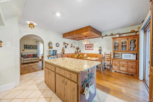a living room with stainless steel appliances kitchen island granite countertop a sink and cabinets