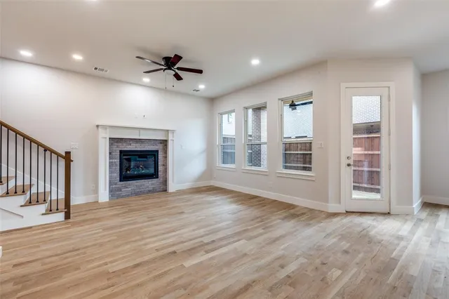 an empty room with wooden floor fireplace and windows
