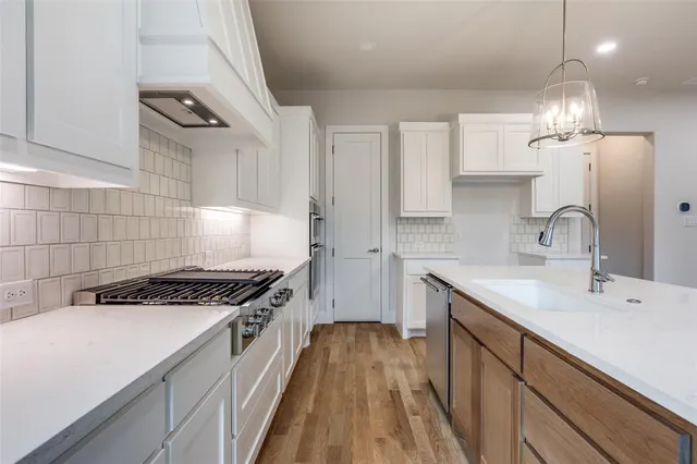 a kitchen with kitchen island stainless steel appliances a sink a stove and a wooden floors