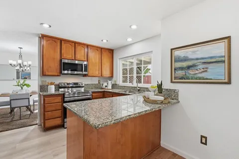 a kitchen with granite countertop a stove top oven a sink a counter top space and cabinets