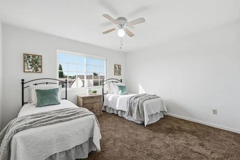 a bedroom with two beds and ceiling fan