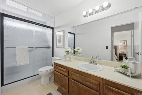 a bathroom with a granite countertop sink a toilet a mirror and shower